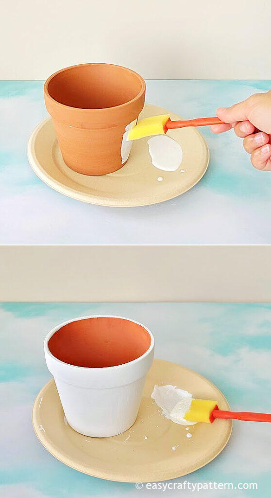Applying white paint on clay pot.