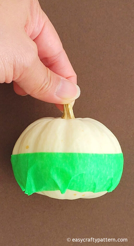 Wrapping pumpkin with painter tape.