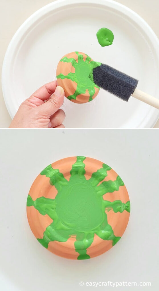 Painting green on the clay saucer.